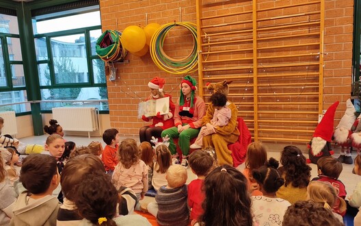 Alle klassen verzamelen om het kerstvrouwtje met haar elf en rendier te verwelkomen.