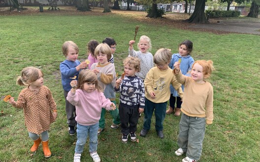 De kleuters dansen met een blaadje in de hand.