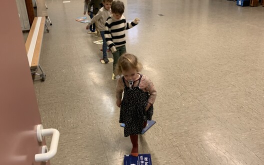 Kleuters wandelen de turnzaal uit over een weg van boeken