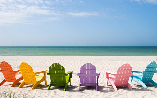 afbeelding van het strand met veel gekleurde stoelen in vakantiestemming
