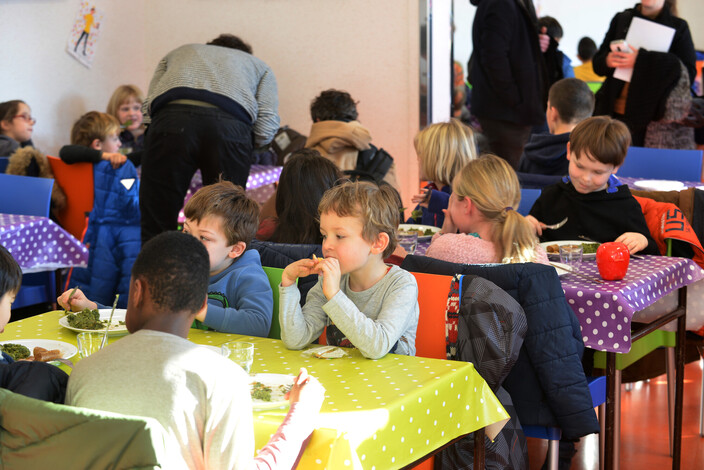 Kinderen die in de refter een warme maaltijd eten.