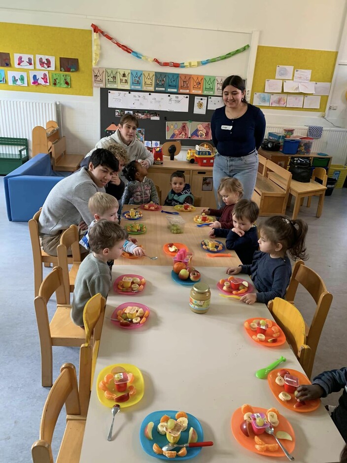 kinderen zitten samen aan een tafel met een bordje fruit
