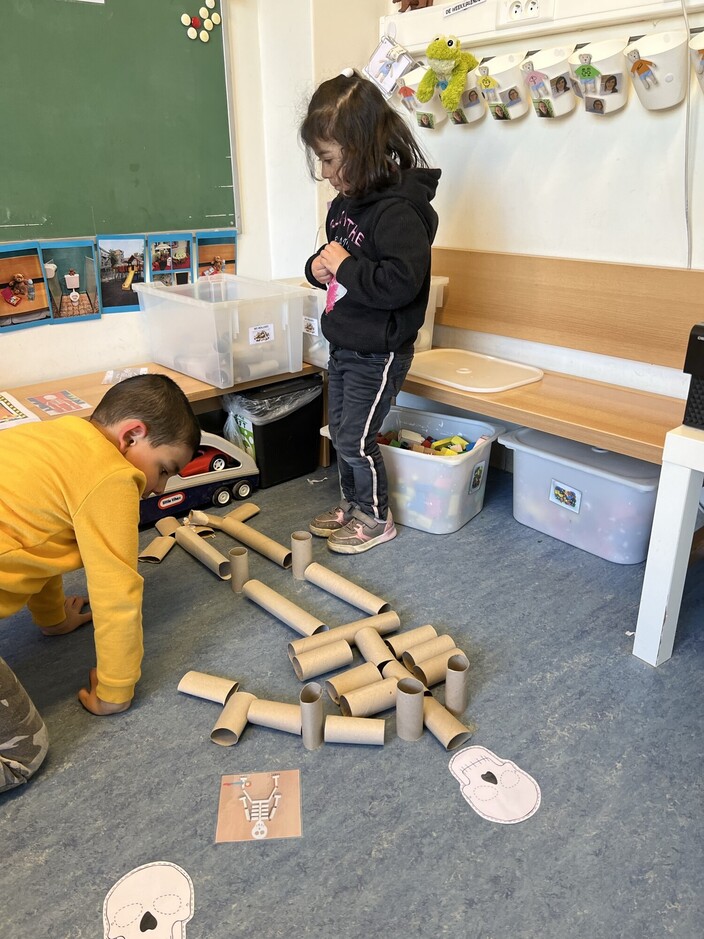 Een skelet bouwen met houten blokken en toilet rollen.