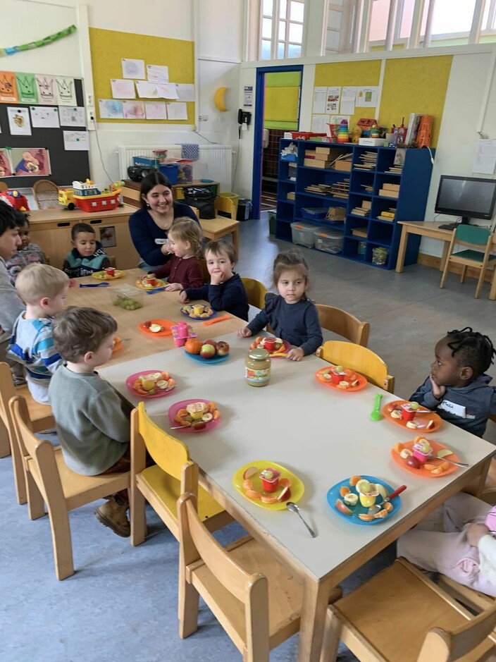 kinderen zitten aan tafel met een bordje fruit voor zich