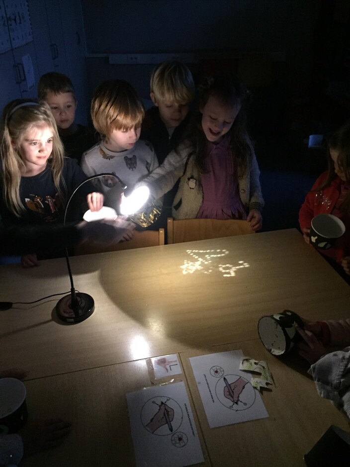 Kinderen experimenteren met lamp en potje.